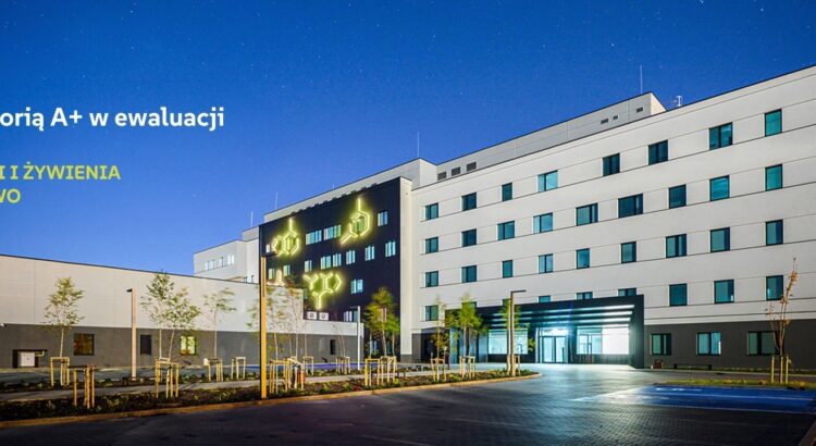 Nowoczesny budynek instytutu z podświetloną elewacją i wzorami chemicznymi w nocnej scenerii.